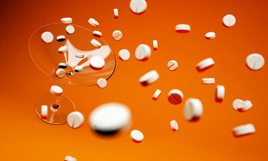 Pills falling on a martini glass