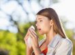 A woman with pollen allergies, sneezing into a tissue.