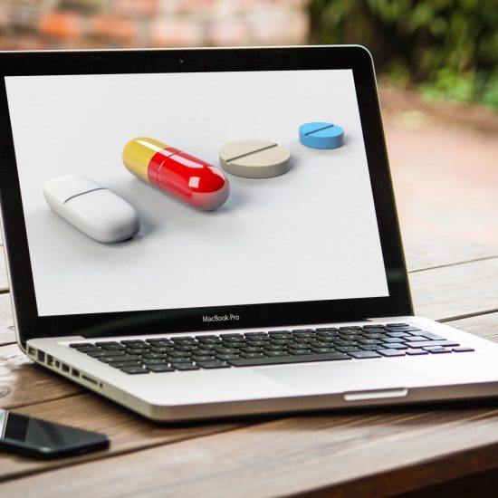 Laptop computer on table, shows different options for buying prescription drugs online.