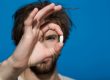 Man holding a white pill in his hand. Pill is in focus against a bright blue background, showing the importance of Zoloft for people with depression.