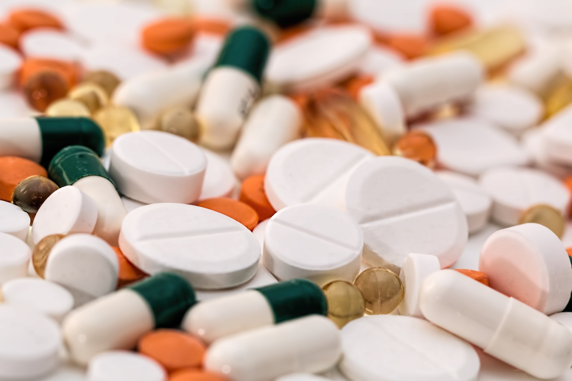 A variety of pills of different colours all together on a table, indicating that many prescription medications can be bought online, making getting your pills easier than every before.