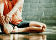 Man seated on floor stretched out right leg to exercise and strengthen ahead of knee surgery